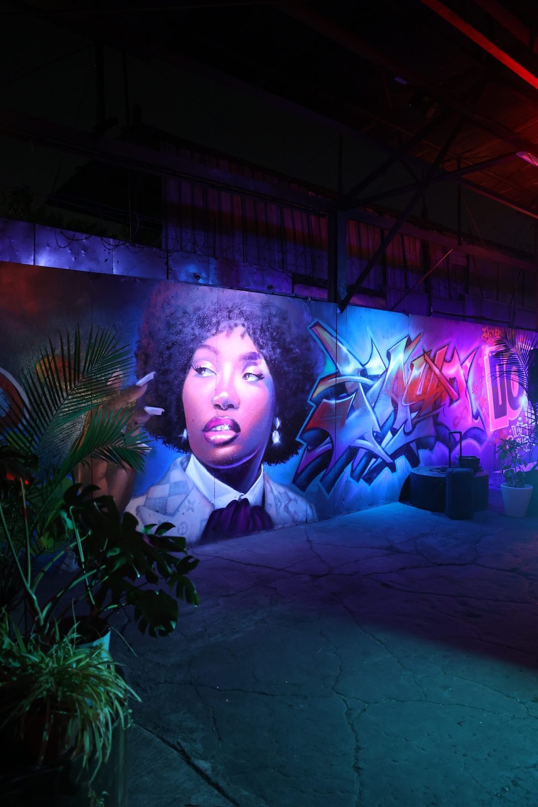 Portrait mural and graffiti wall lit in blue and purple at Complete Studio