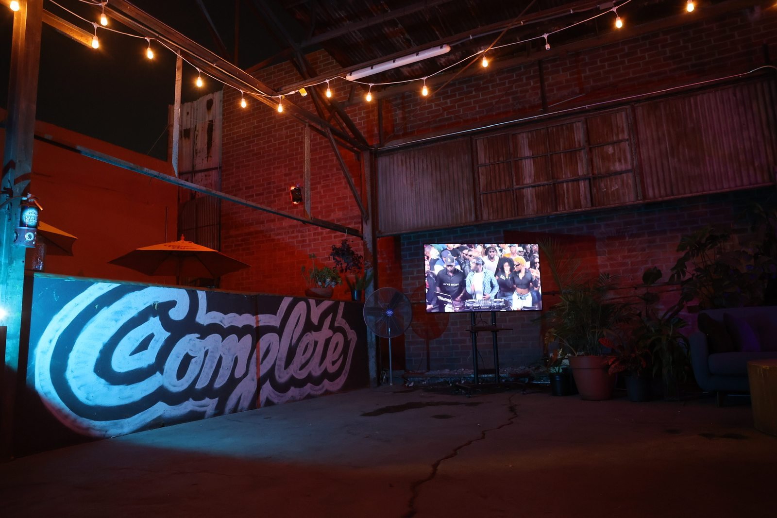 Complete mural beneath string lights beside the studio lounge