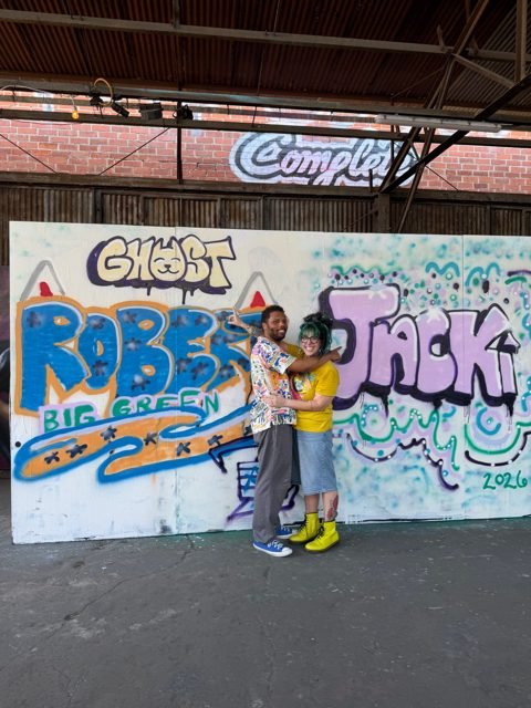 Two workshop guests beside their colorful graffiti pieces