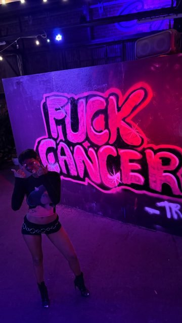 Workshop guest beside pink graffiti lettering under purple lights