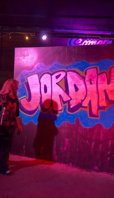 Workshop guest beside a pink JORDAN graffiti piece