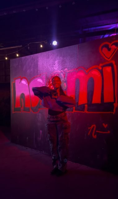 Workshop guest beside colorful graffiti under pink lighting