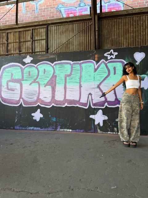 Workshop guest beside a pastel green and pink graffiti piece