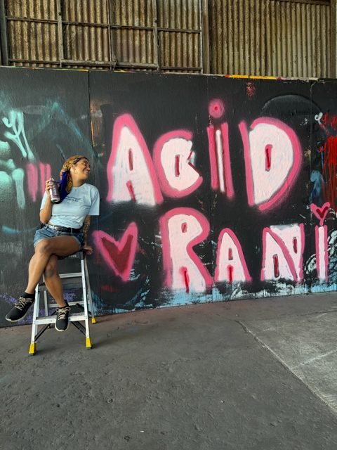 Workshop guest beside pink graffiti lettering
