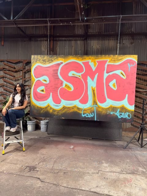 Workshop guest beside a red and yellow graffiti piece