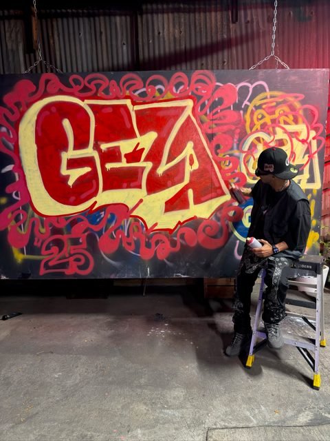 Workshop guest beside a red and gold graffiti piece