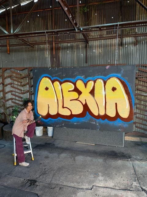 Workshop guest with a yellow ALEXIA graffiti piece