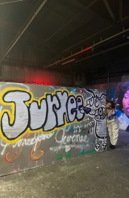 Workshop guest beside a yellow and silver graffiti wall