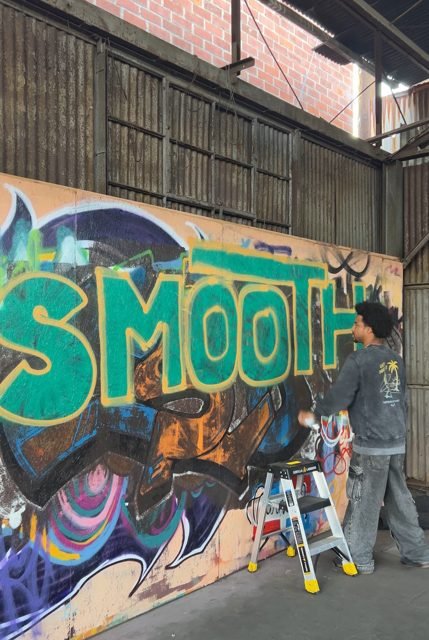 Workshop participant painting green graffiti lettering