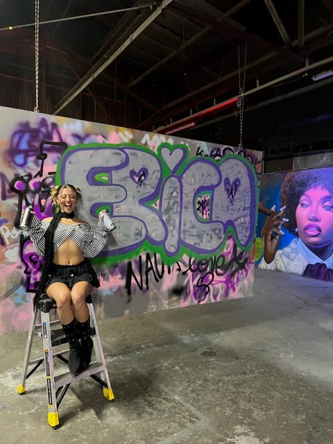 Workshop guest beside a purple graffiti piece