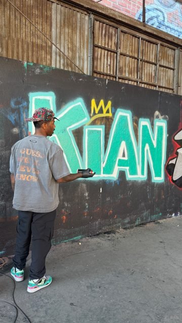 Workshop guest painting a green graffiti piece